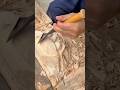 Carving intricate patterns on wooden block using sharp metal chisel tool in workshop