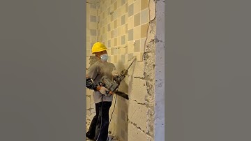 Demolition Work in Progress: Using a Power Drill to Break Down a Concrete Wall