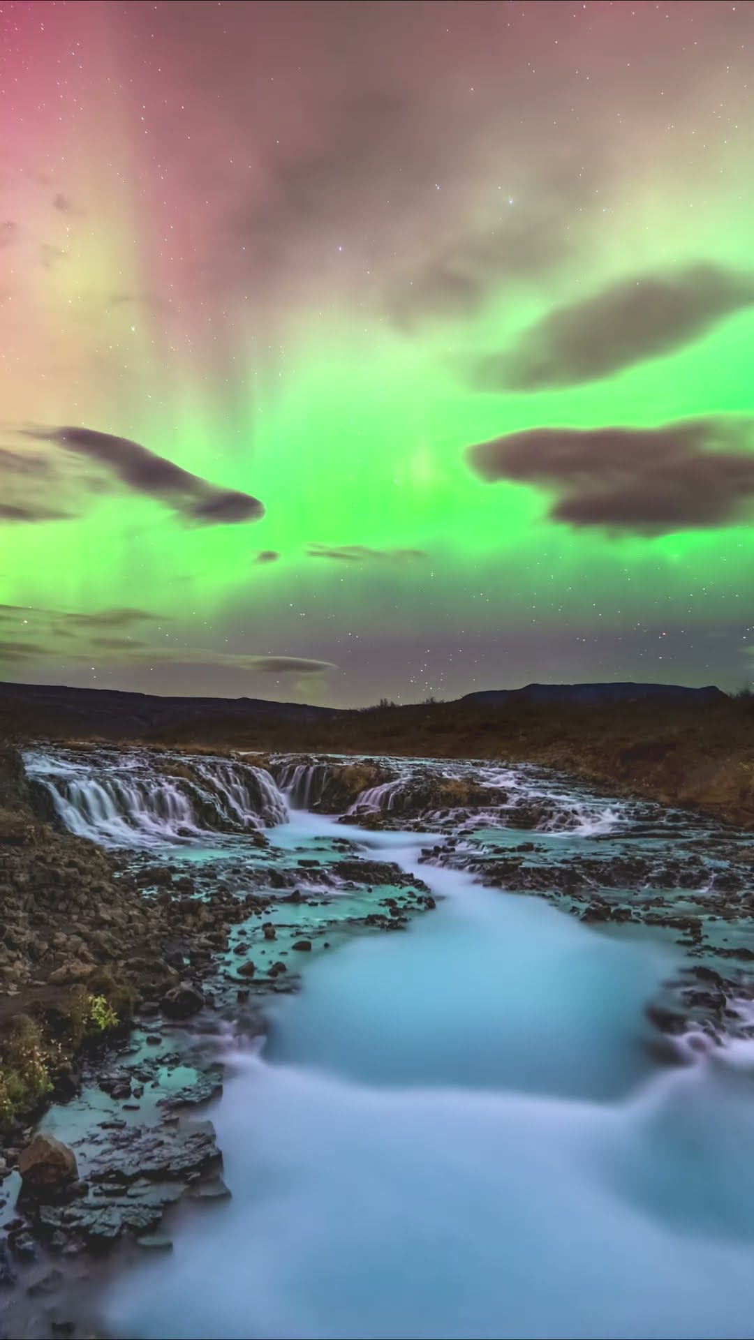 A geomagnetic storm illuminates Iceland's stunning Brúarfoss waterfall with green and red hues ?