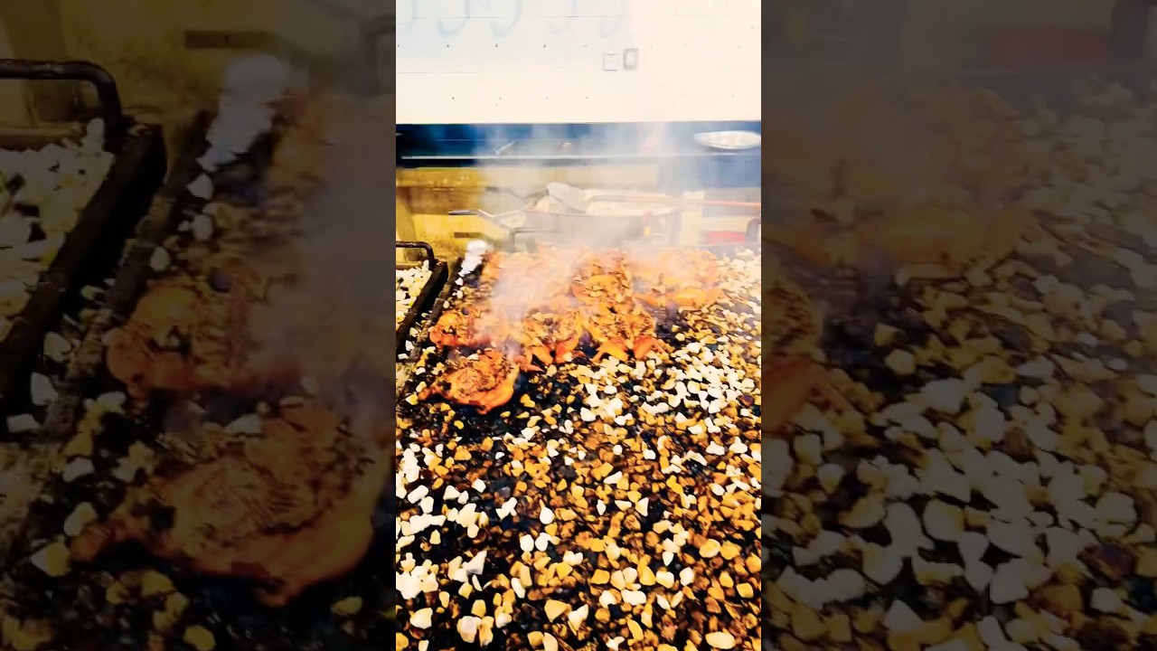 Traditional OMANI cooking grilling camel meat and chicken over hot stones 