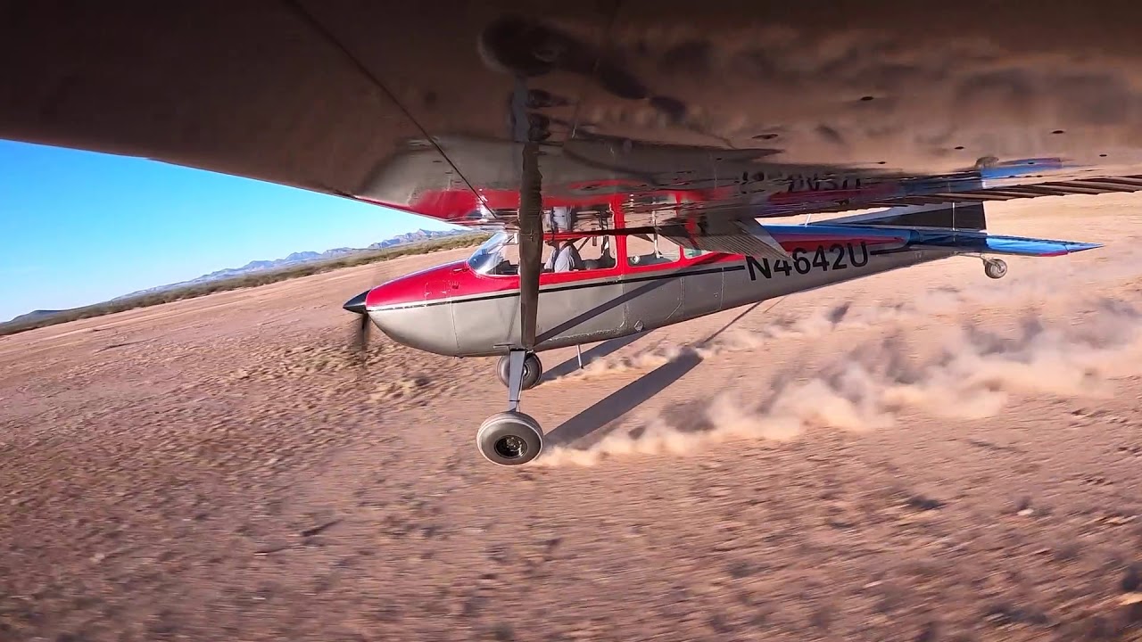 Cessna 180 Skywagon landing in the dirt.