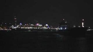 Cargo ship shows its backside to the Queen Mary 2 travelling sideways at night down River Mersey