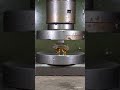 A plastic bottle containing oil is crushed by a hydraulic press.