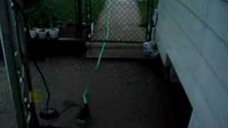 Flooded side yard with pump running to drain water
