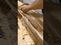 carefully smoothing a large decorative wooden board by hand to create detailed wavy pattern surface