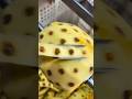 peeling fresh yellow pineapple fruit using a specialized manual metal machine in a workshop