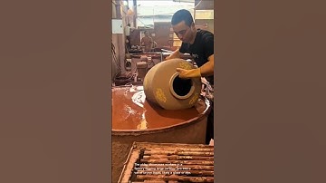 Ceramic jar dipping: workers coating large jars in brown liquid
