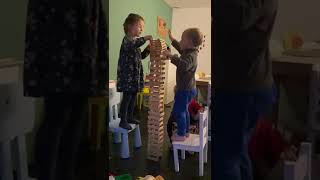 Boy falls off chair while putting together wooden tower and its collapses (Slow Motion)