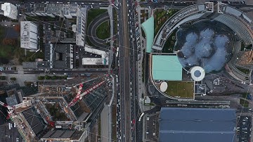 Aerial birds eye overhead top down panning view of traffic in streets leading along tall skyscrapers