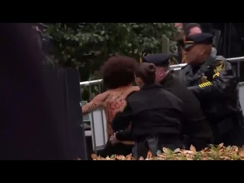 Topless protester lunges towards Bill Cosby outside courthouse