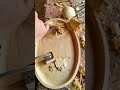 Carving an oval wooden tray surface with a sharp manual chisel tool to create a smooth hollow area