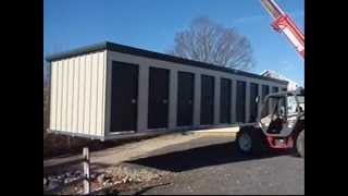 This video shows 2 self storage buildings being delivered, prefabricated, on a truck. The unloading of the storage buildings only 