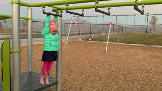 Girl swings from monkey bars and falls on the ground as she attempts to get back on the platform