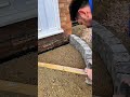 Landscaper screeds sand base level for curved patio edge