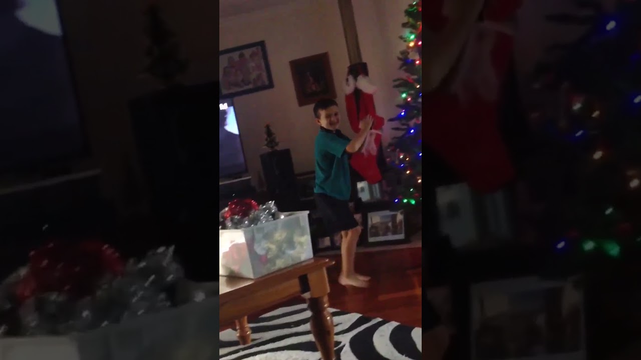 Boy dances looks a ballerina near Christmas tree then falls on floor and bumps head