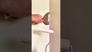 Using a paint roller and scraper to create a clean, straight edge while painting a wall