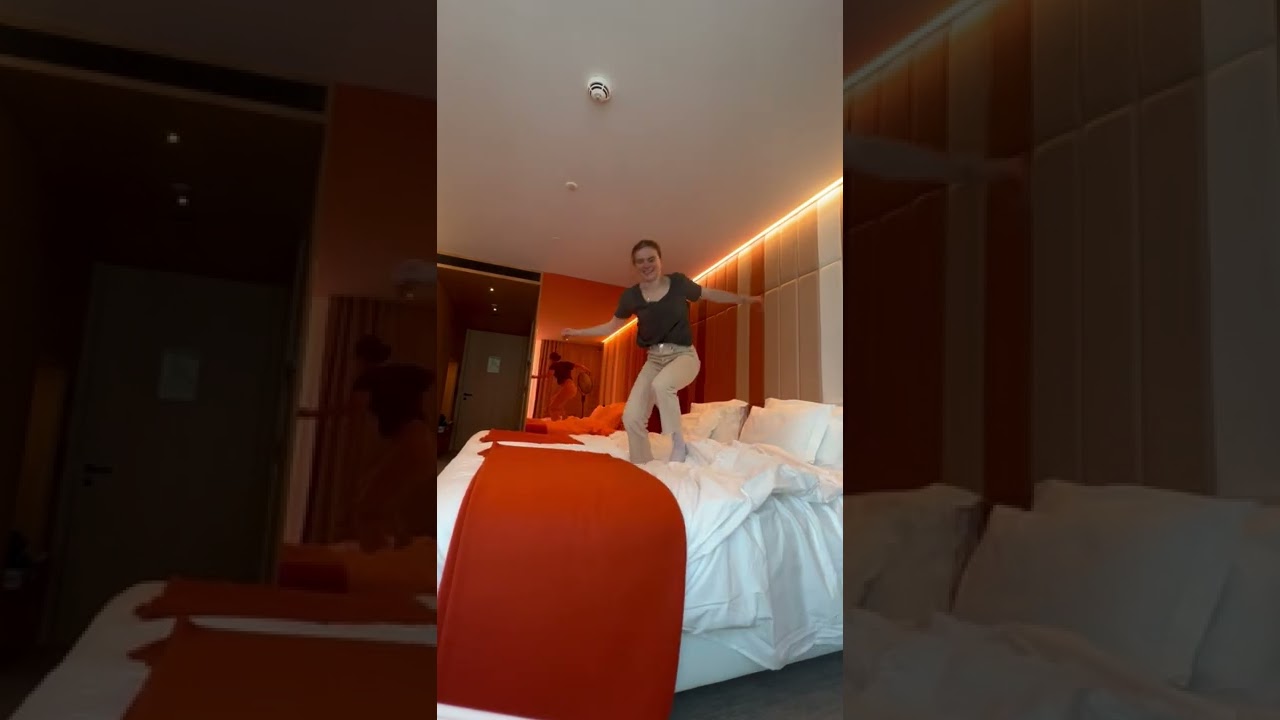 Person does a flip on a hotel bed, then falls off the bed!