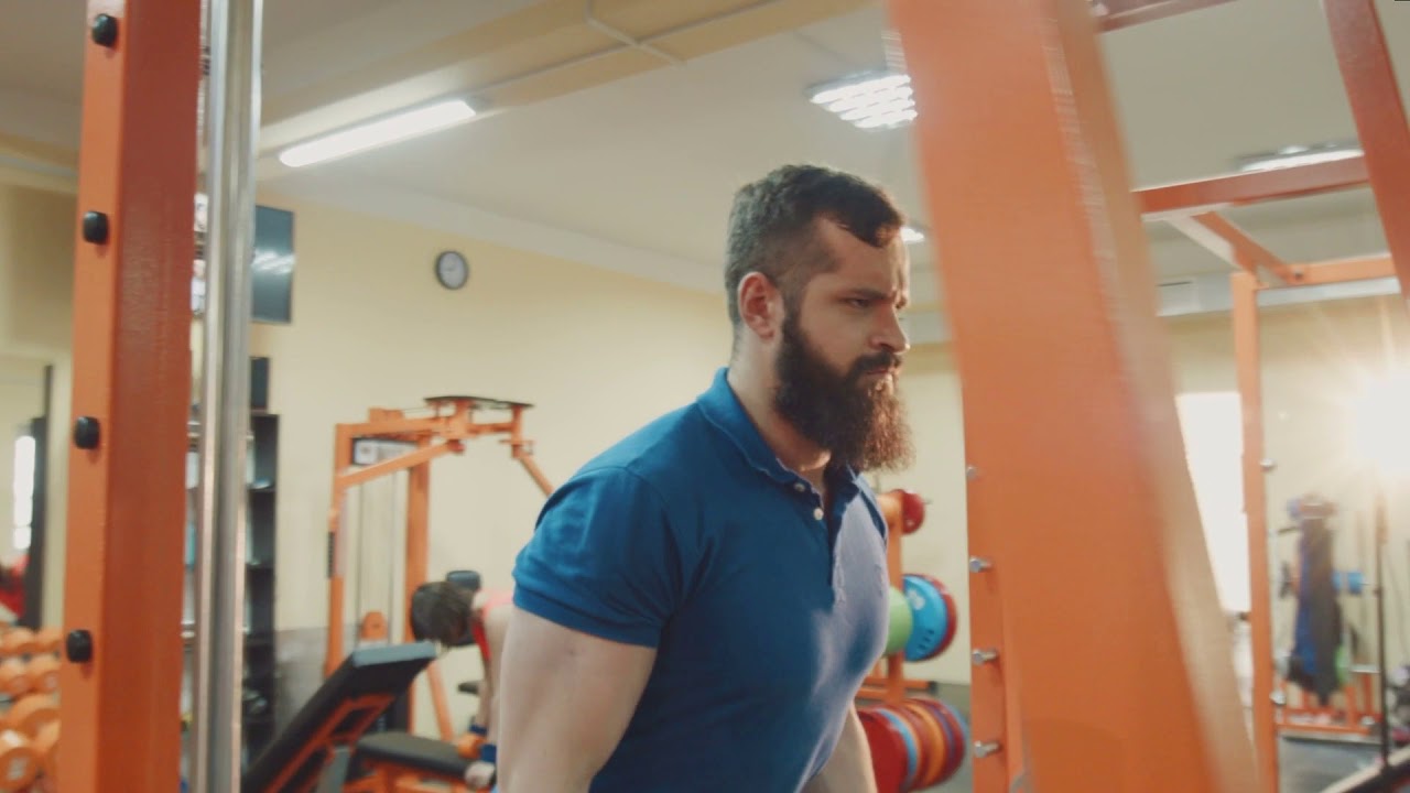 the guy is engaged in a gym on the exercise machine lift heavy weight