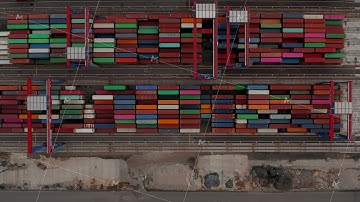 Overhead birds eye aerial view of colorful cargo containers and industrial cranes arranged in rows