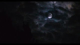 Peculiar pale moon drifting through night clouds