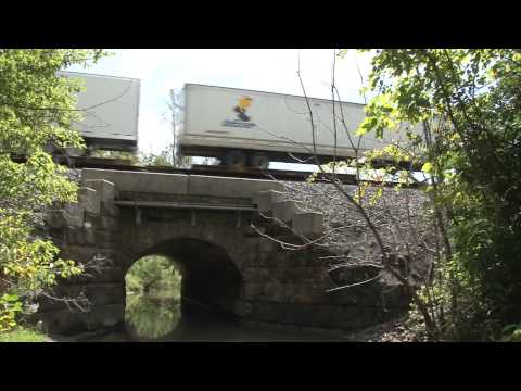 Plum Creek Aqueduct 0:55 Westbound CSX container and trailer train over Plum Creek Aqueduct. Containers are one high. Where is the height restriction on the B&O main? SD70AC # 4513 leads. ES40DC # 5473 follows. 0:00 Plum Creek Aqueduct as new in the 1840's for the Pennsylvania and Ohio Canal. 0:08 Plum Creek in Kent. Ohio has many Plum Creeks. 0:20 Downstream side of Plum Creek Aqueduct in 2010. 1:42 Top side of Plum Creek Aqueduct. Three tracks. The left track is Shelly Materials RR joining the middle track, the eastbound line of this double track CSX main. 1:50 Upstream side of Plum Creek Aqueduct. This is the face drawn when Plum Creek Aqueduct was new in the 1840's. 2:08 May be a cover for a stock report, or stock sales flyer, or broadside, for the Pennsylvania and Ohio Canal (P&O). 2:13 Shelly Materials RR Headquarters and Prime Mover EMD SD18 #321. The Pennsylvania and Ohio Canal, P&O, was a successful private canal between Akron, OH, and the Beaver Canal branch of the Pennsylvania Canal. Today, the P&O ROW is a CSX double track main, the double track B&O main of eastern Ohio. Kelly Materials RR also has a line on the upstream side of Plum Creek Aqueduct connecting to CSX on the other side of the aqueduct. American Canal Society describes the P&O as obliterated. Here is a P&O structure in use. Plum Creek Aqueduct is not very accessible. The equally beautiful, now abandoned, Plum Creek Viaduct, a couple hundred feet upstream from the Plum Creek Aqueduct, built for <b>...</b>