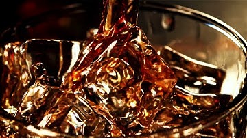 Super Slow Motion Whiskey with Splashes Flows Into a Glass of Ice