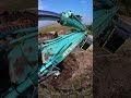 excavadora kobelco 210 cargando raices y troncos en la volqueta