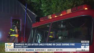 Charges filed after child found in cage during fire