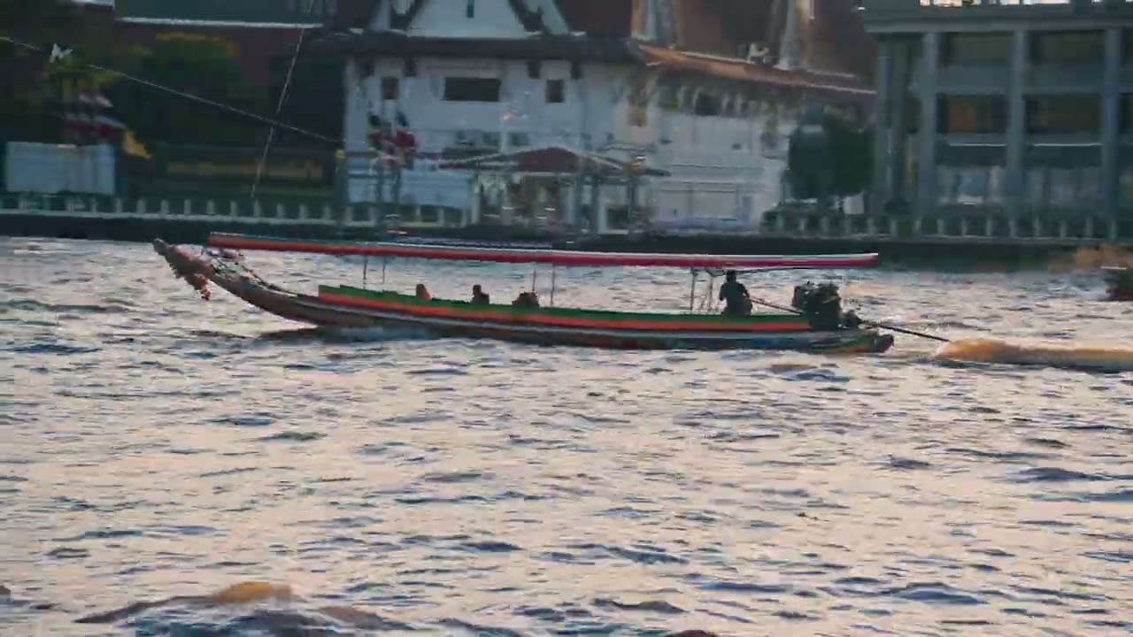 Traditional longtail boat transports tourists sailing on the Chao Phraya river in Bangkok with Wat