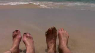 Two Pairs Of Feet Wiggling On A Beach