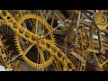 Close-up view of a complex golden clockwork gear mechanism with cogs and chain