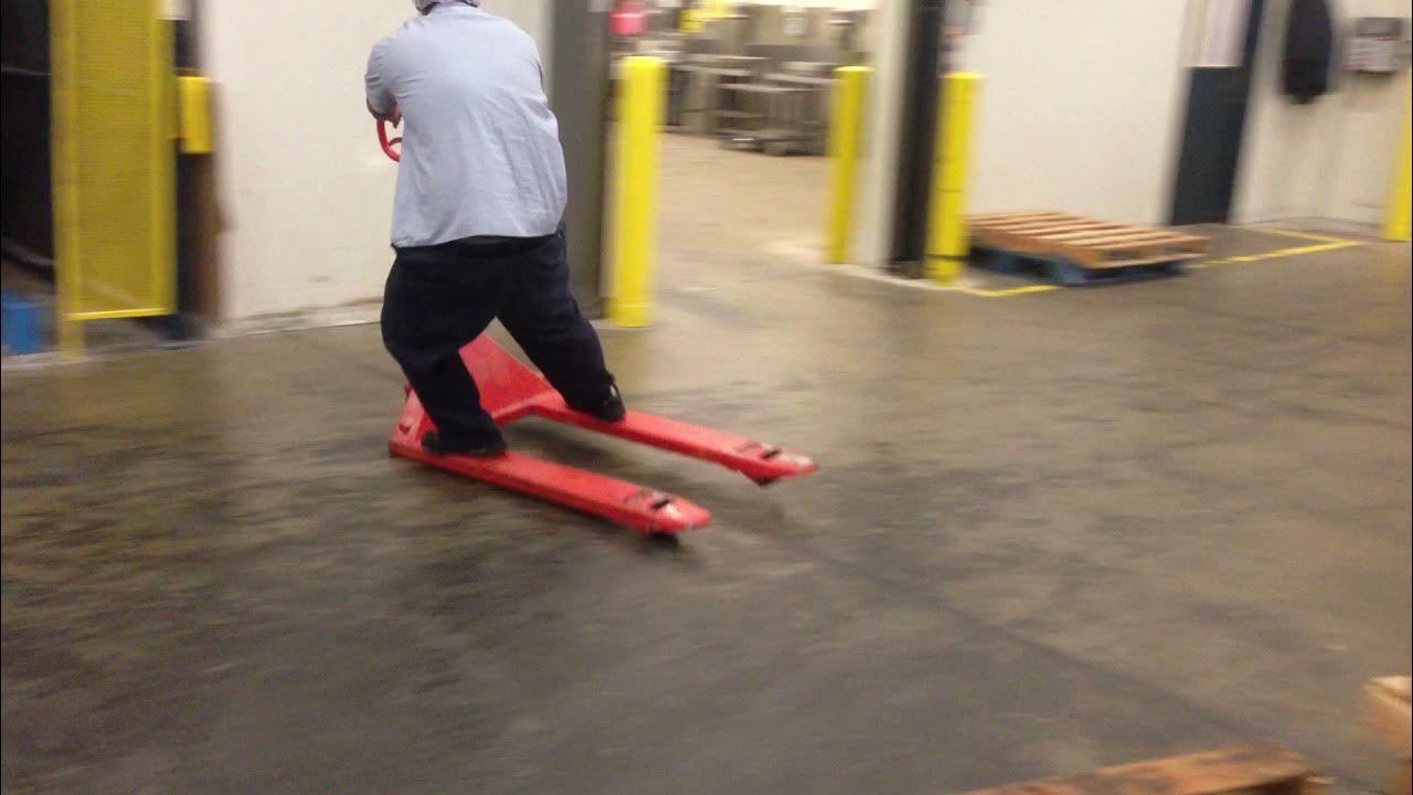 worker-riding-pallet-jack-slides-in-style-on-reaching-destination