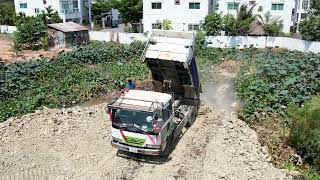 Dump truck unloading stone filling up with Bulldozer komatsu D31p Working push stone into the water