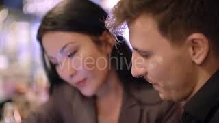 Businesspeople Discussing Pictures on Tablet at Bar