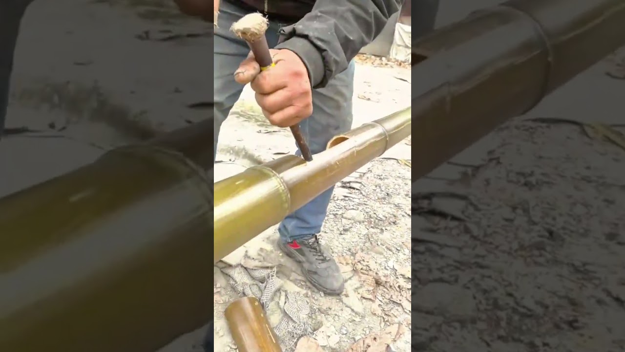 carving a small opening into a long bamboo pole using a sharp metal tool 