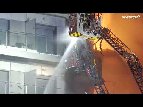 Los bomberos rescatan con dos grúas a dos personas del interior del edificio en llamas en Valencia