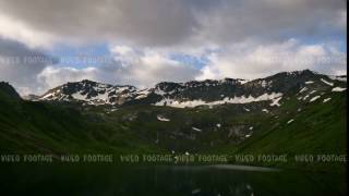 timelapse of High Snowy spring mountains with sunset clouds and peaceful mirror lake