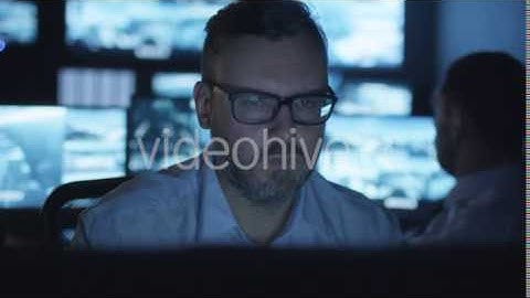 Security Officer is Working on Computer in a Dark Monitoring Room Filled | VideoHive 14742641