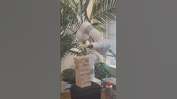 Romantic robot extends a rose and plays Jenga.