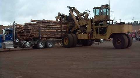 Huge wheel loader log stacker unloading logging truck