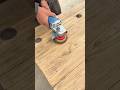 sanding a flat wooden surface using a blue electric hand power tool to create a smooth texture