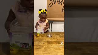 Baby pours apple juice into a cup