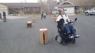 Mark driving around boxes while in his new head-controlled power wheelchair
