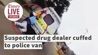 Suspected drug dealer handcuffed to police van before driving away