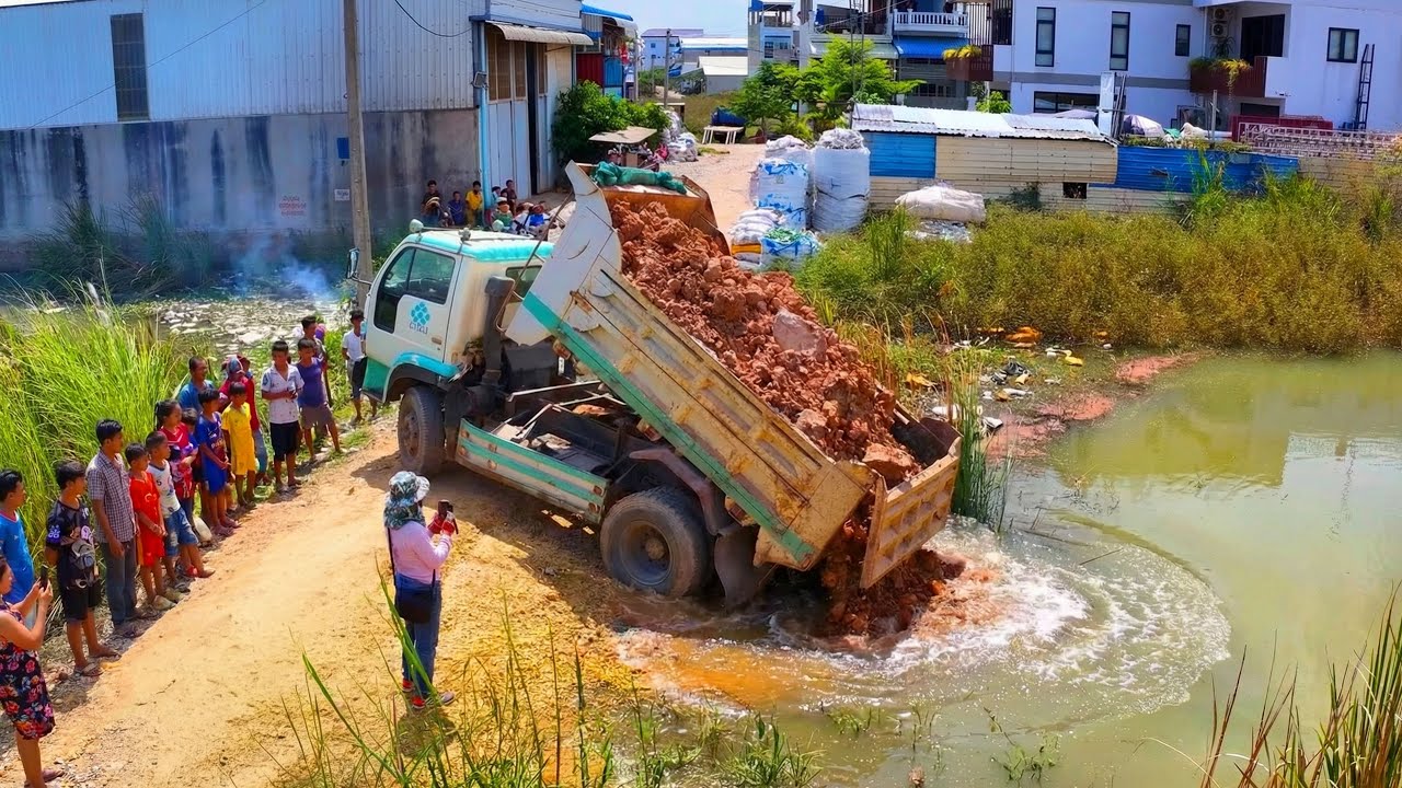 Extreme work Landfill build school project .Truck transport soil with Bulldozer Push soil to water