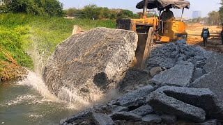 Small Dozer Pushing Hard Rock And Concrete Filling Lake With Small Dump Trucks