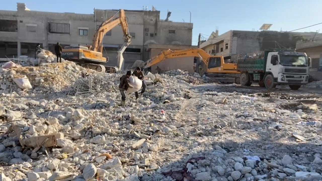 فرق الدفاع المدني تساعد الأهالي في بلدة عزمارين في رفع أنقاض المباني المهدمة وترحيلها