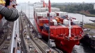 A huge Ship weighs trucks in a narrow aisle channel.Корабль давит тягочи в узком проходе канала