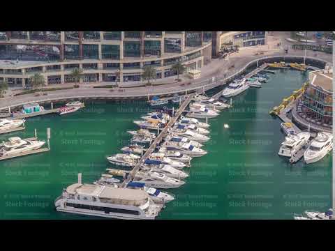 Aerial view on yachts floating in Dubai marina timelapse. White boats are in green canal water.