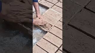 making red clay bricks manually using a traditional rectangular wooden mold on ground outdoor